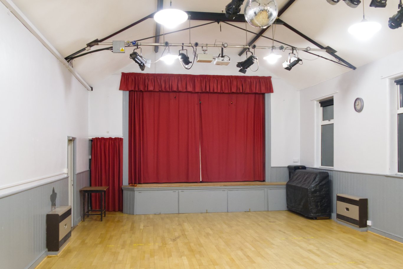The main hall, with its wooden floor, stage and red curtains